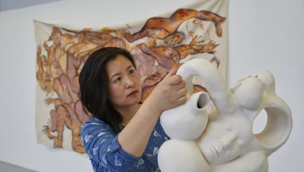 An artist manoeuvres an elaborate sculpture into position inside an art gallery