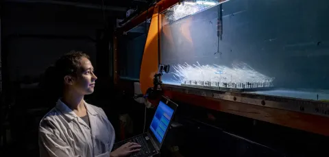 A researcher with a laptop measuring underwater flow in a water tank