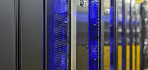 The IRIDIS 6 research computing facility. A series of servers in silver casing with blue and yellow network cables in the background.
