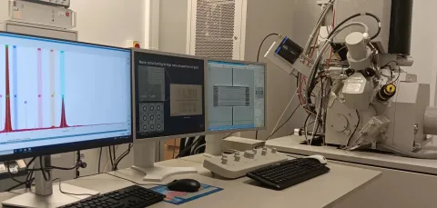 Three monitors and a scanning electron microscope for focused ion beam tool