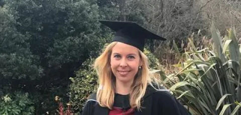 Dr Jess Jarvis smiles at the camera in her graduation gown and cap