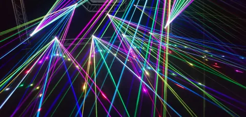 Colourful laser beams intersecting against a dark background.