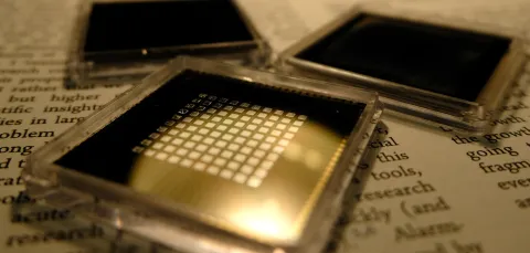 three small square microchips placed on the pages of a book with visible text.