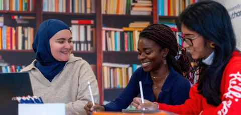 Students working together using digital tablets in a library-style setting.