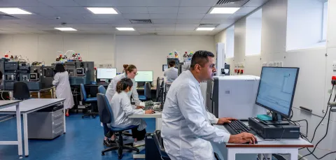 A modern laboratory with scientists working at computers and scientific equipment.