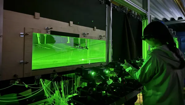 Researcher operating laser-based flow visualisation equipment in an experimental fluid mechanics laboratory