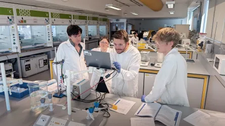 A group of students near the open laptop in the laboratory