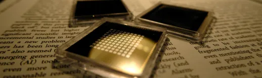 three small square microchips placed on the pages of a book with visible text.