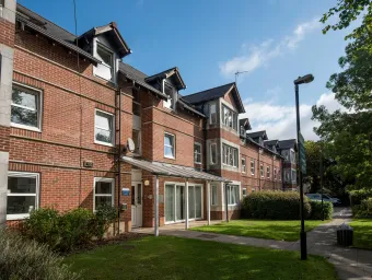 Exterior view of red brick, two storey accommodation building on a sunny day.