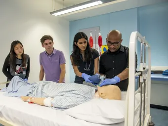 Students practising clinical skills on a dummy in the hospital skills rooms.