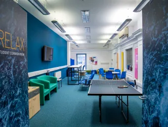Empty student common room with sofas, table tennis table, chairs and desks.