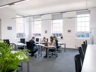 Students studying at desks in a bright, airy room.