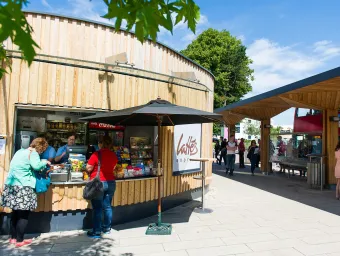 People buying snacks from a small kiosk beside a bus stop.