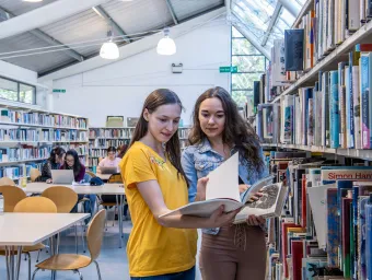 Two students browsing books in a bright, modern library.