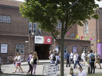 Outside of the red brick Student Union building, with people walking in front.