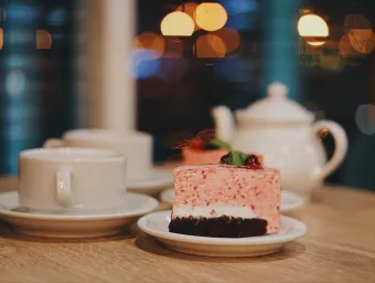 Tea cups, teapot and a slice of cake on a table in a cafe. 