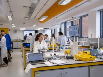 Students in lab coats working at chemistry lab benches. 