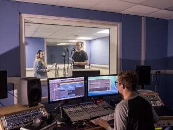 Studio manager working with 2 singers in the music studio.