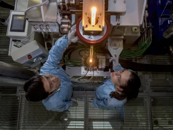2 students in lab coats looking at tower of light from fibre tower.