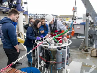 Students gathered around some tanks on the deck of the Callista ship