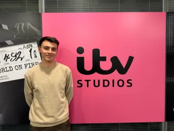 BA Spanish and Linguistics Graduate, Joe Dobinson standing by a sign for ITV studios.