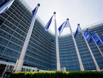 European parliament building with EU flags flying outside.