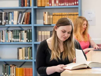 Nineteenth century literacy students studying books in the library.