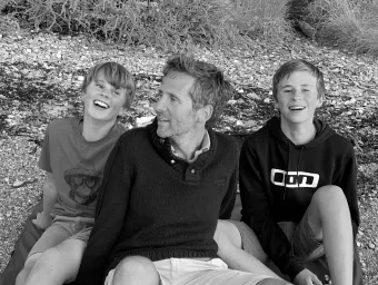 A monochrome photo of Crispin Malpas and his sons in a casual moment, enjoying each others' company.