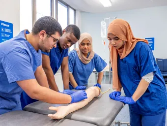 Fahmia and other student doctors studying an arm