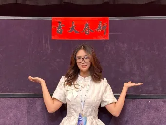 Shuheng Zhand standing in front of a banner in Chinese