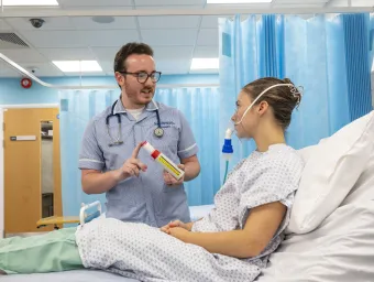 Student nurse helping patient with breathing equipment