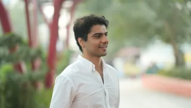 Law graduate and entrepreneur Rohit is standing looking to the right of the camera. There are out of focus trees and shrubs behind him.