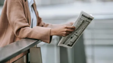 Hands of a person holding an open newspaper