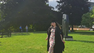 MPhys Astrophysics with a Research Year graduate Martyna wearing graduation gown and hat on a campus lawn.