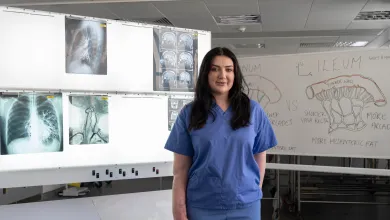 Medical student Becca standing in a teaching room with medical imaging displays.