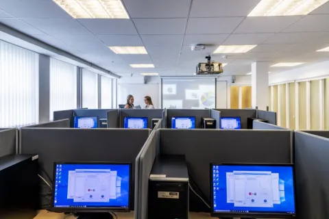 A view of workspaces in the social sciences experimental lab, with two students talking in the background