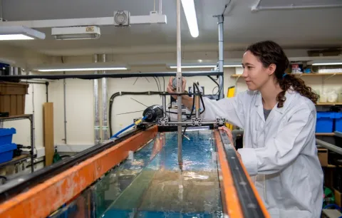 A student standing over a tank in the coastal lab facility