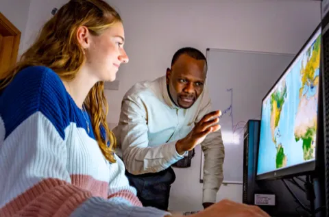 A member of the Southampton Geospatial team delivers training to a young person sitting in front of a screen with a visualisation of mapped data