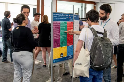 Researchers discussing an academic poster at an event