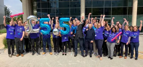 Southampton clinical trials unit researchers and staff outside their building, holding balloons saying £5.5 million