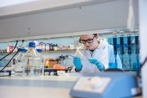 A researcher in a lab, examining a slide