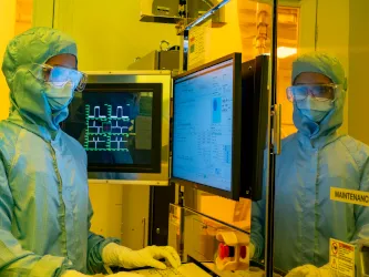 A researcher in a cleanroom suit and wearing a protective glasses, uses the electron beam lithography (EBL) facility