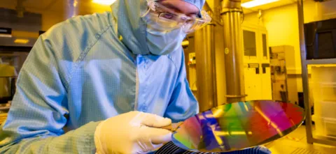 A researcher in a cleanroom suit with a 200mm wafer in the nanofabrication cleanroom