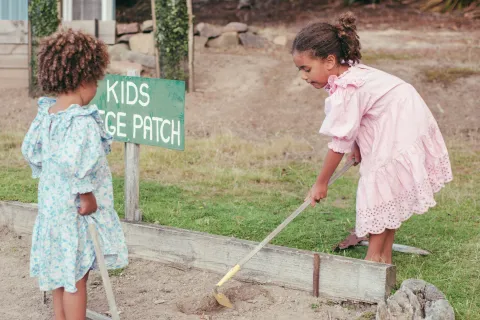 Two children gardening at a kids' veggie patch.