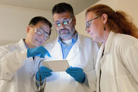 Three researchers gather round a tablet