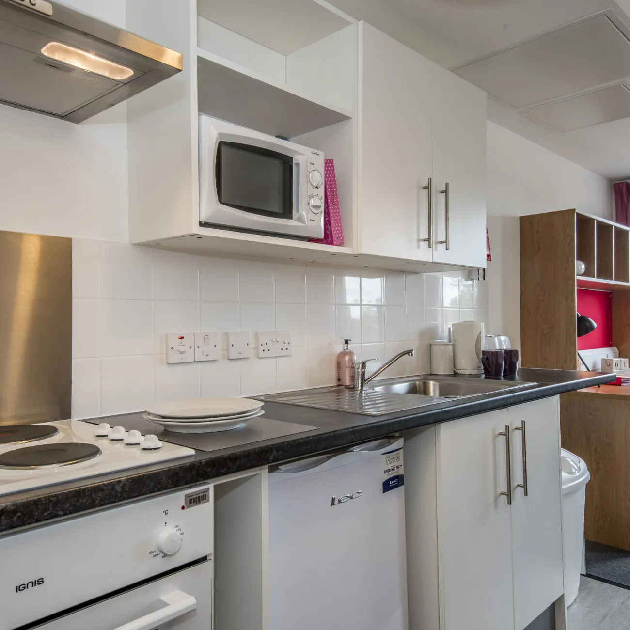 A modern studio flat showing desk and kitchenette.