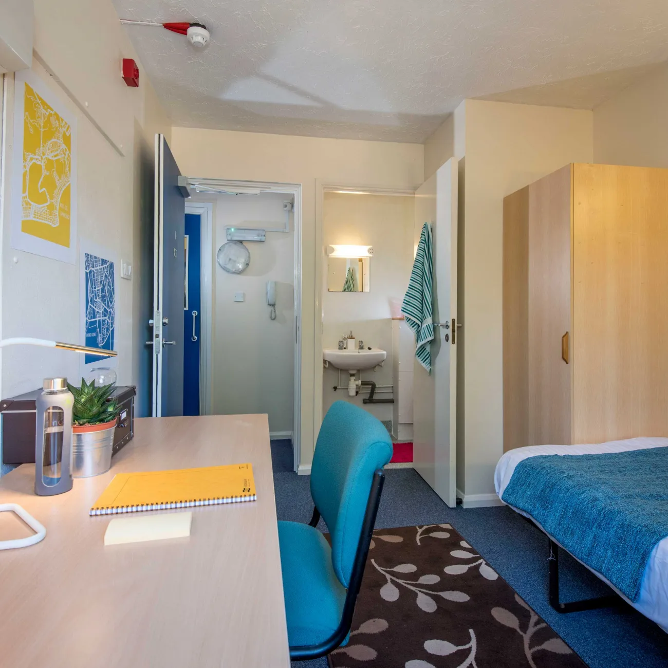 Student bedroom showing bed, desk and entrance to bathroom.