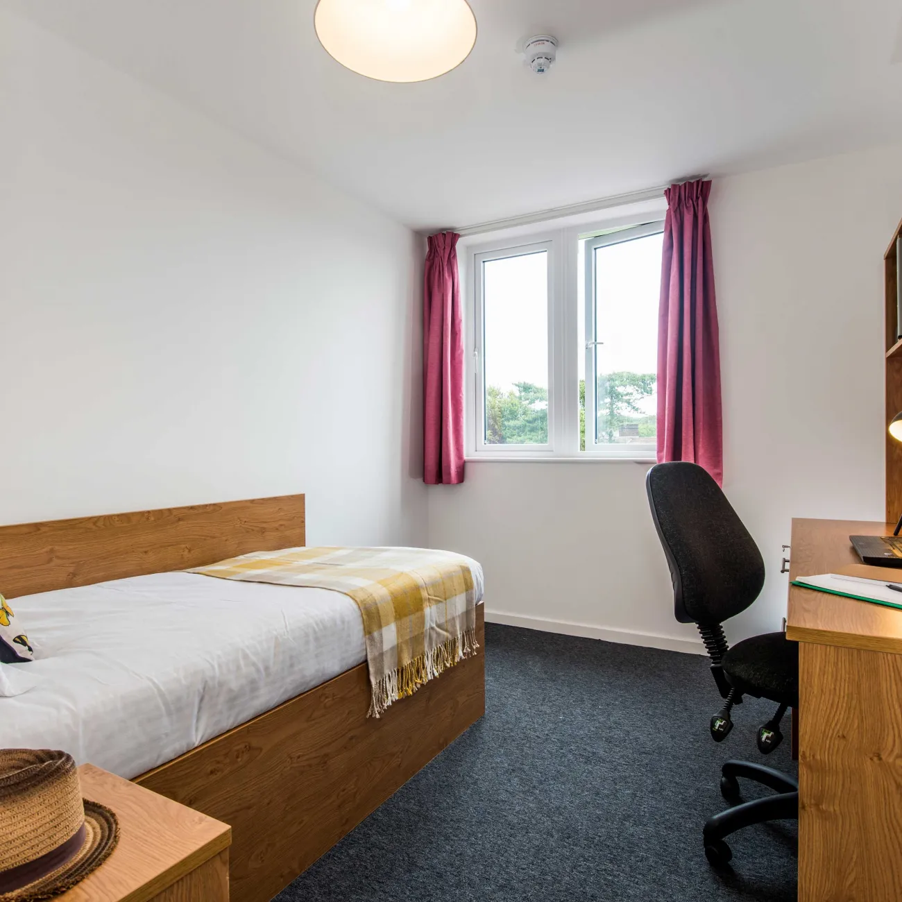 Modern student bedroom with bed and desk.