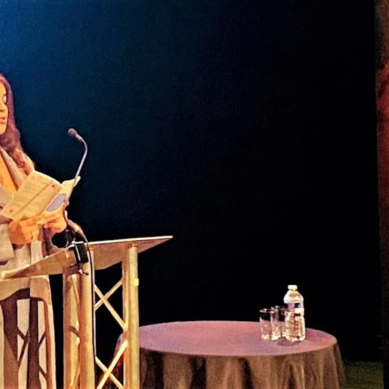 A young poet, Kaycee Hill, speaks on a stage at a launch event for a poetry anthology in Winchester.