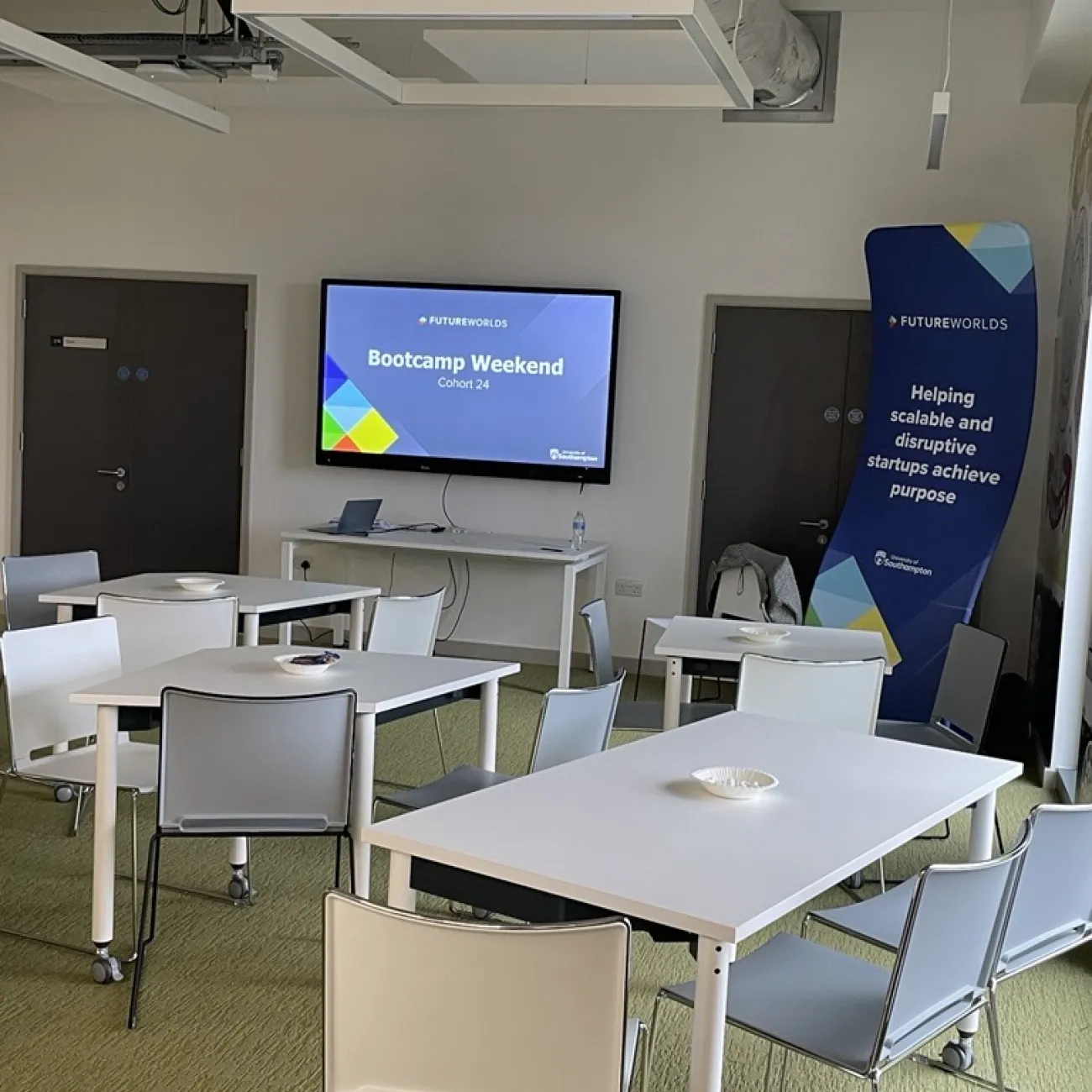 Conference room with tables, chairs, and a screen.